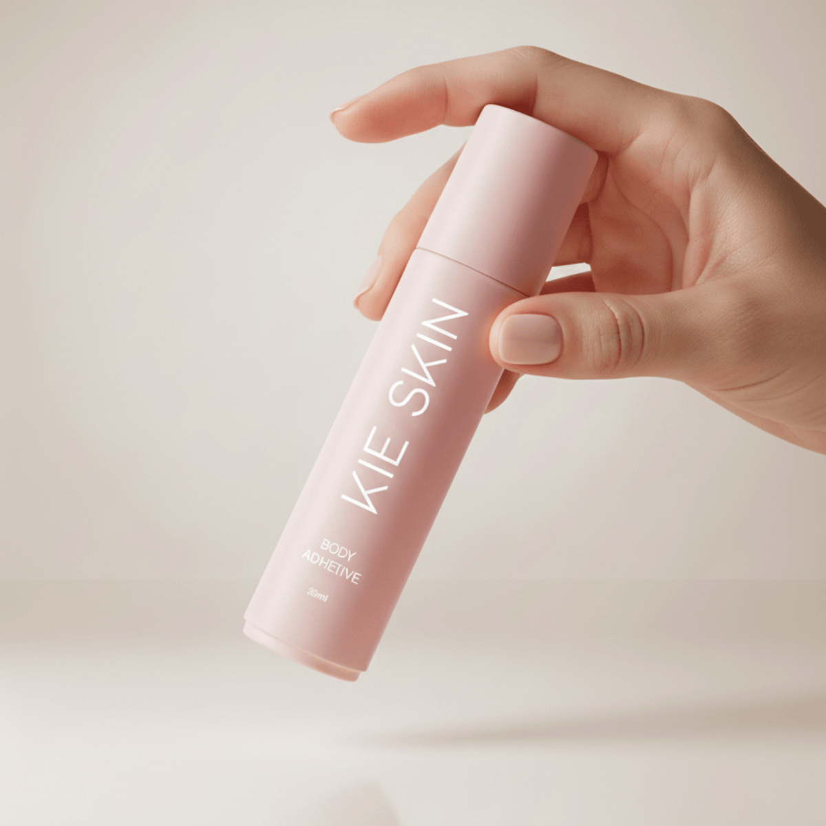 Hand holding the Kie Skin Body Adhesive 30ml roll-on bottle