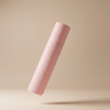 Kie Skin Body Adhesive pink roll-on bottle with cap on, floating against a beige background